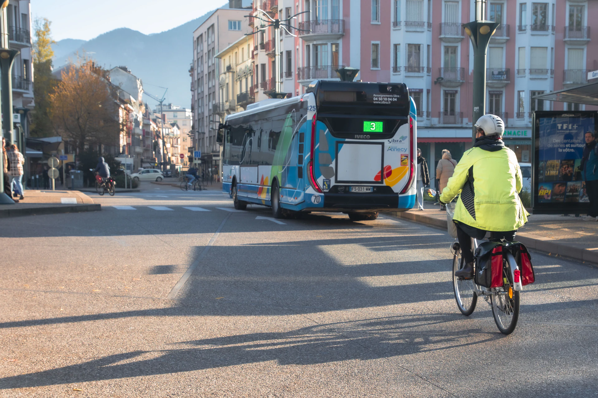 Vue d'une rue animée d'Annecy près de la gare, avec un bus coloré et un cycliste - Mobilités douces et transports - Acteurs Annecy