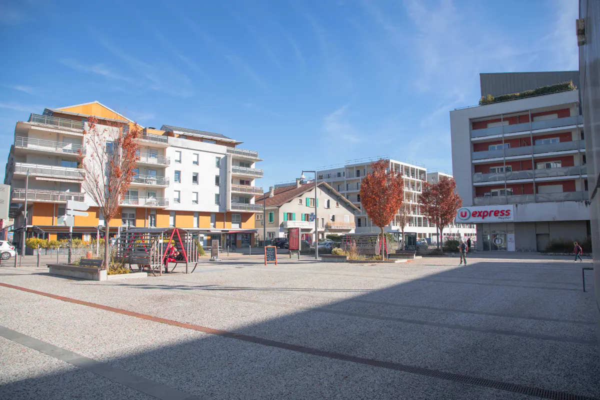 Vue d'une rue commerçante et résidentielle avec des immeubles modernes à Meythet, dans la commune d'Annecy.
